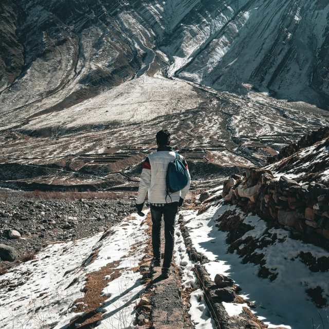 a man walking down a snowy path with backpacks