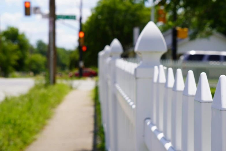 a white picket fence and green grass by the street