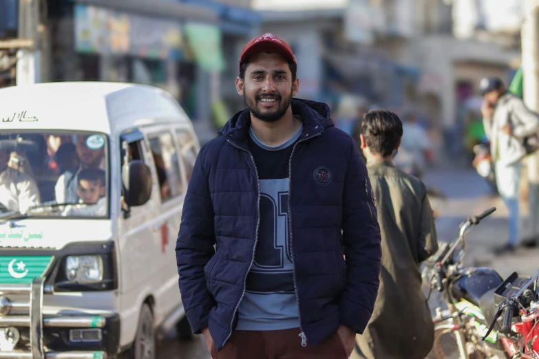 a man in a blue jacket stands on a busy street