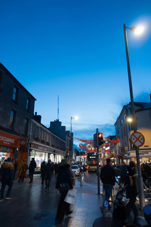 this is an urban scene at dusk, with buildings, cars and pedestrians