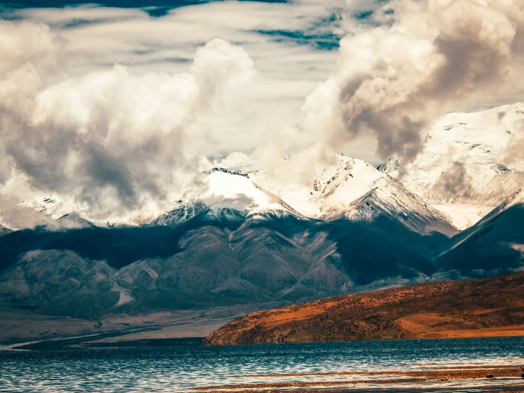 snow covered mountains loom above a body of water