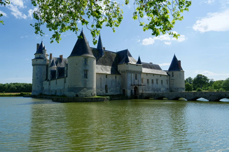 a castle is sitting in the water with one bridge to its left