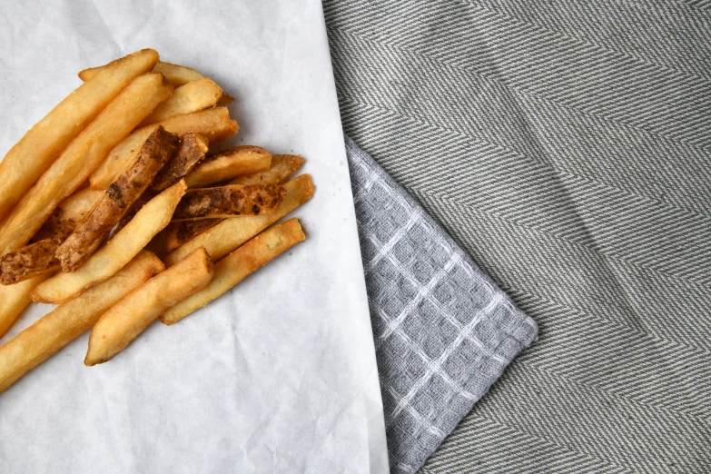 a pile of fries on paper sitting on top of a table