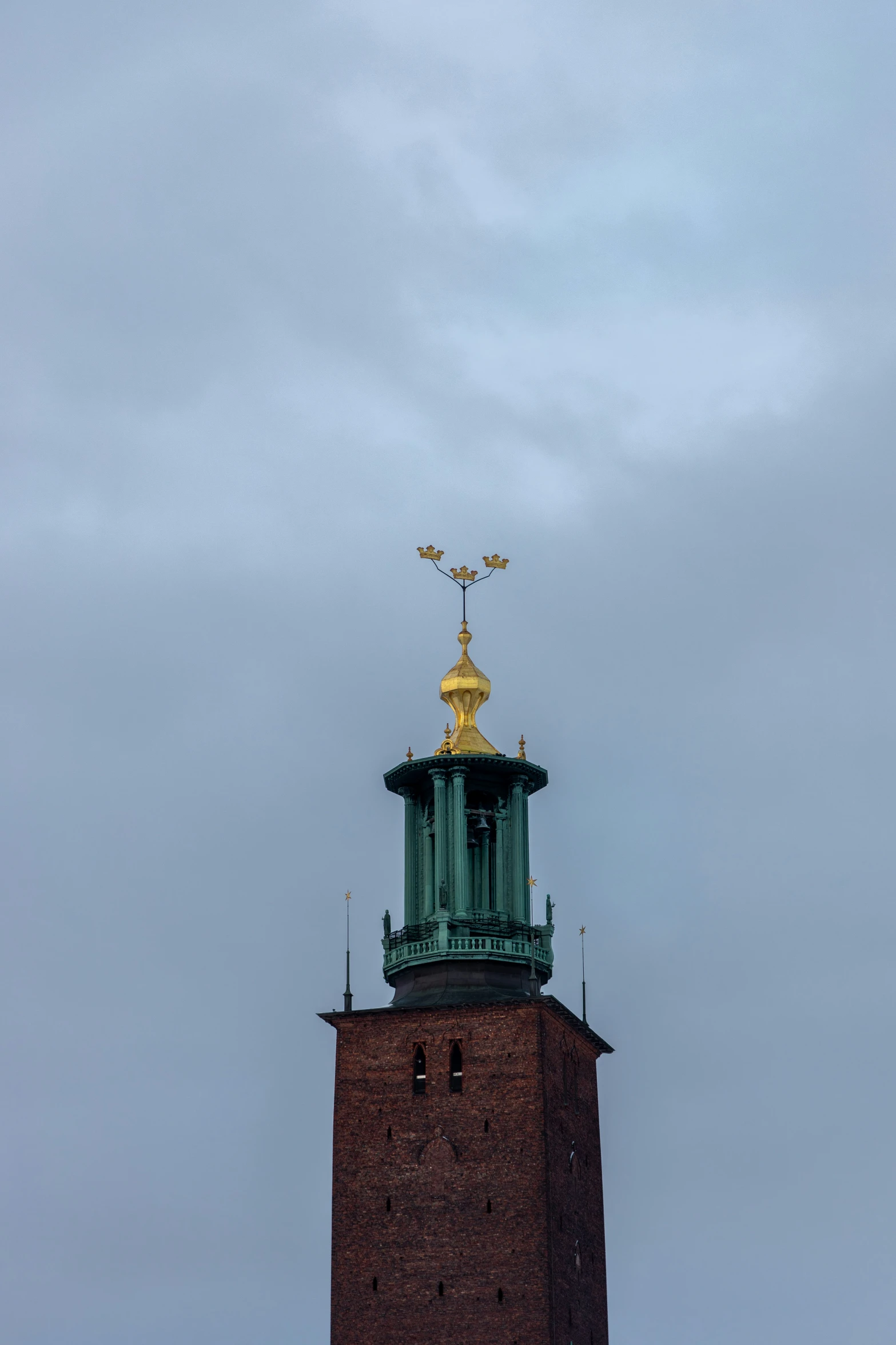 the tall tower with gold trim has a metal statue on top