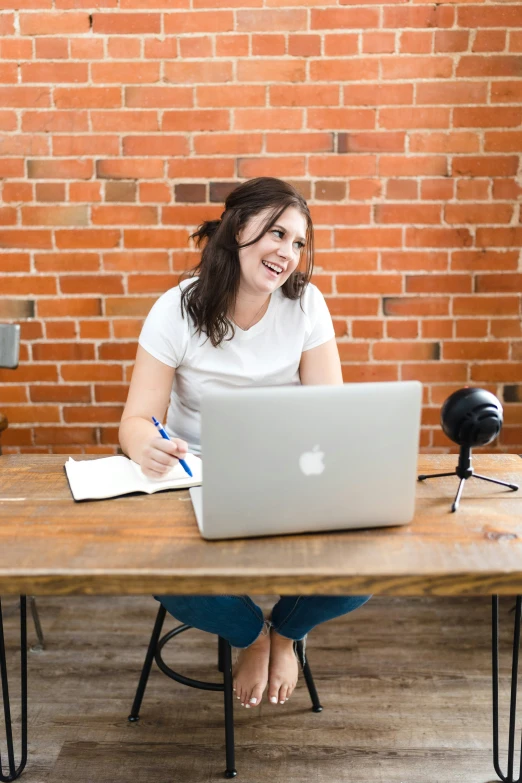 a woman in white shirt sitting at desk with laptop computer