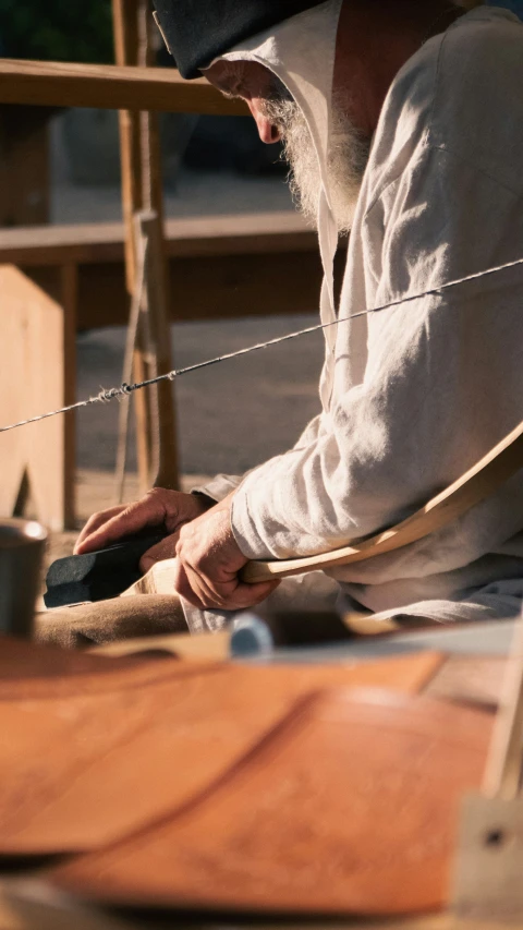 an old man sitting at a table working on a piece of wood