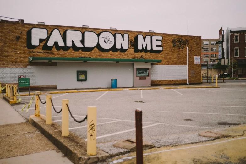 an empty parking lot next to a building with a pardon sign on it