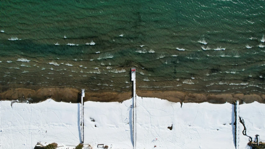 an aerial view of a snow covered beach with a view of the ocean