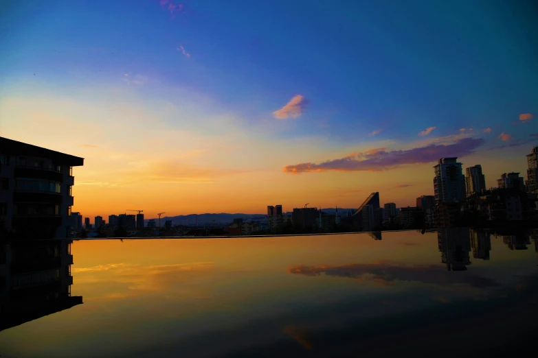 a city in the background reflected on a still water pool