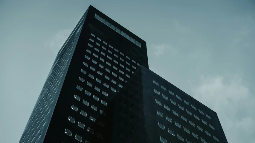 tall building with all black windows against a cloudy sky