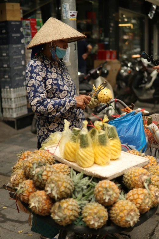 there is a woman selling pineapples on the street