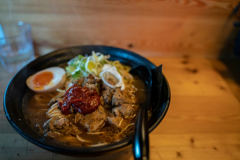 a bowl of noodles with meat and vegetables on the side