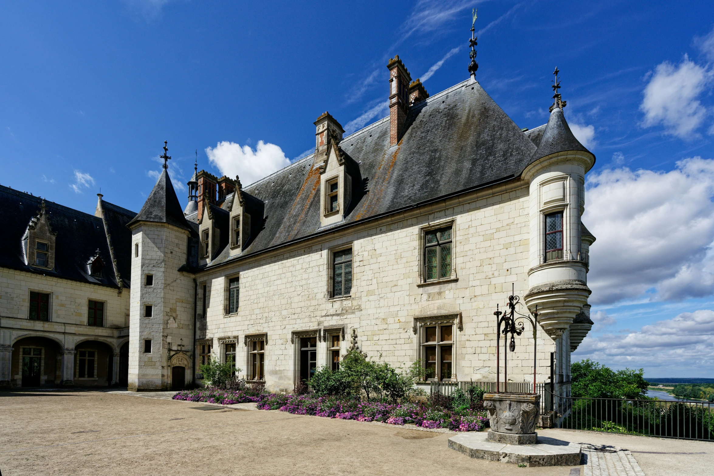 large chateau style home with flower beds in front