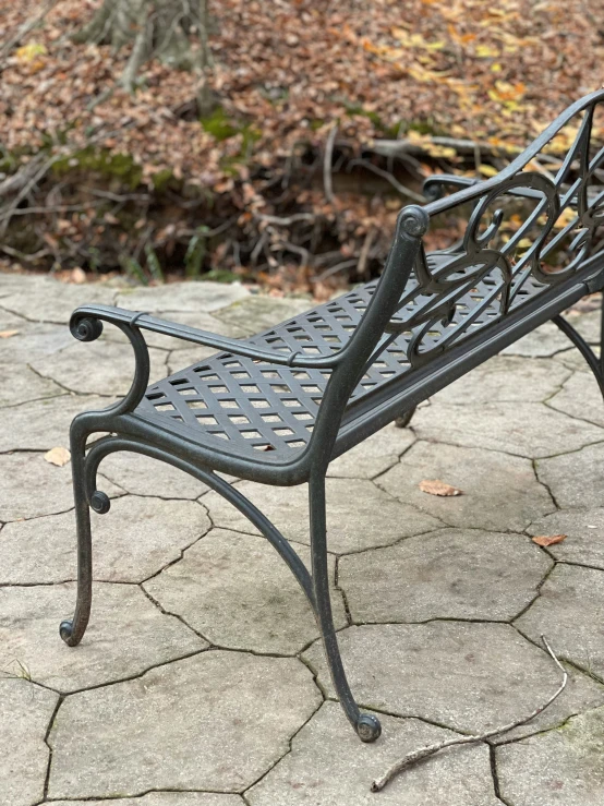 an empty iron bench on a stone patio