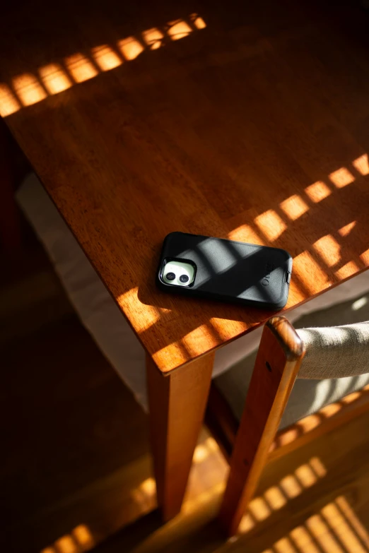 cell phone laying on table, in sunshine with shadow