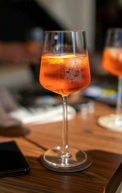 a glass of liquid with a cell phone sitting in front of it