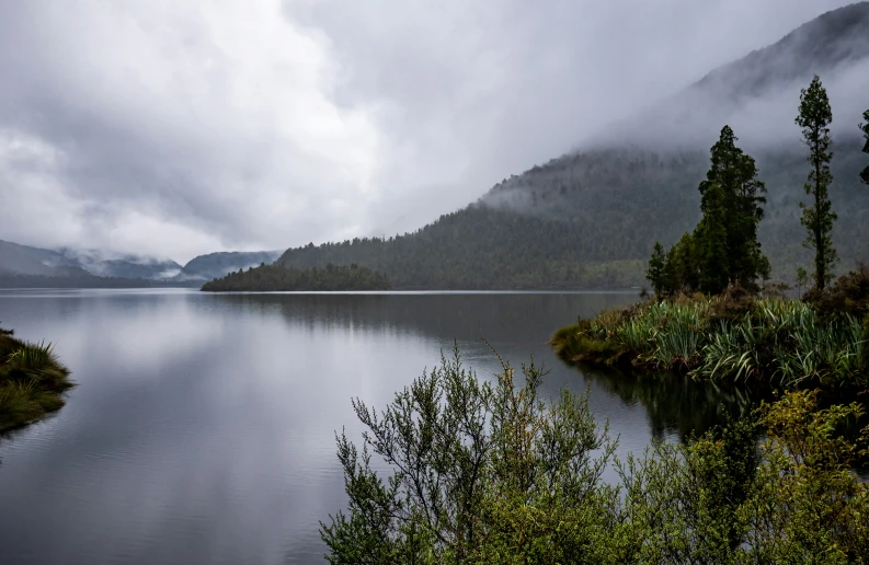 a very scenic image with a body of water surrounded by a green mountain