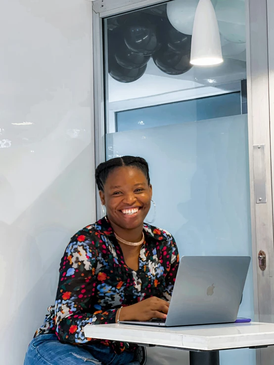 a lady sits in front of a laptop smiling