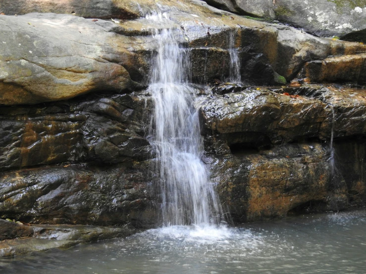 a pool of water is next to a waterfall