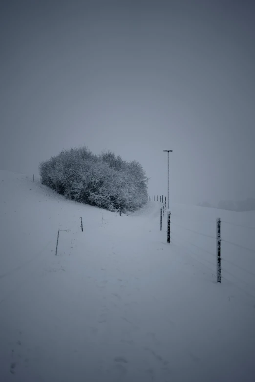 a snowy field next to a fence covered in snow