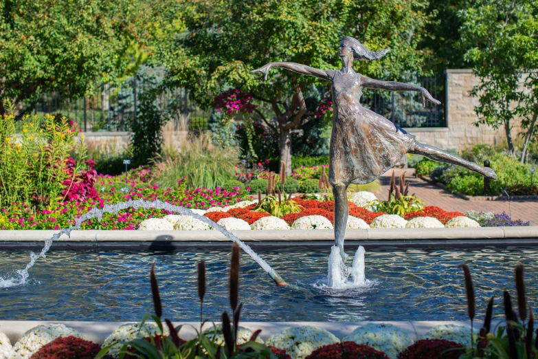 a woman statue in the middle of a flower garden