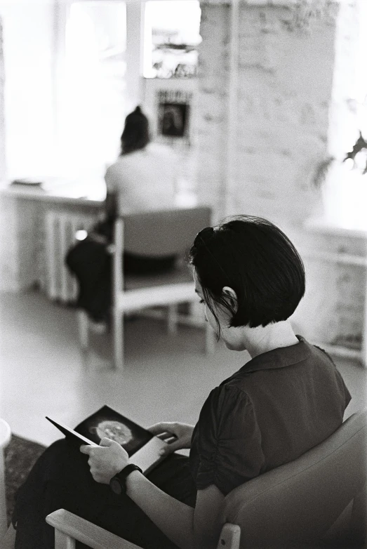 black and white pograph of a woman reading in a chair