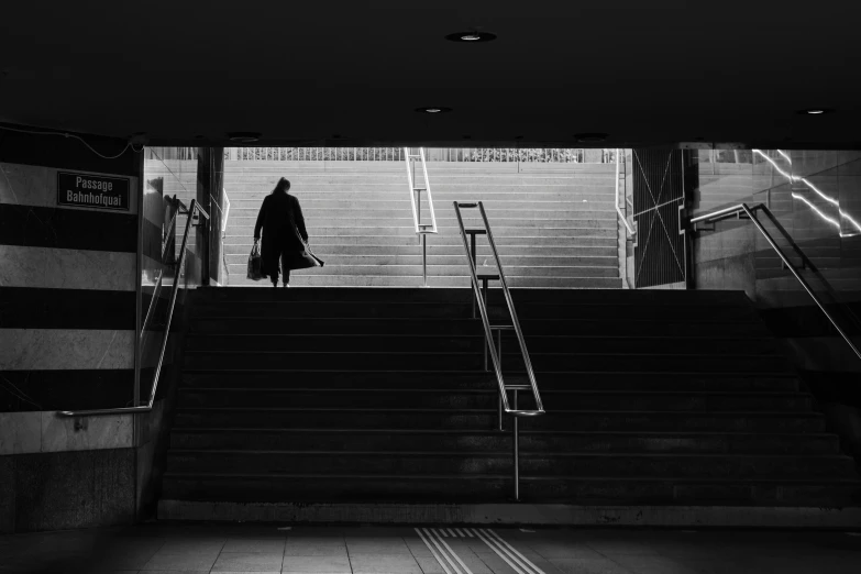 a person in coat and long coat walking down an escalator