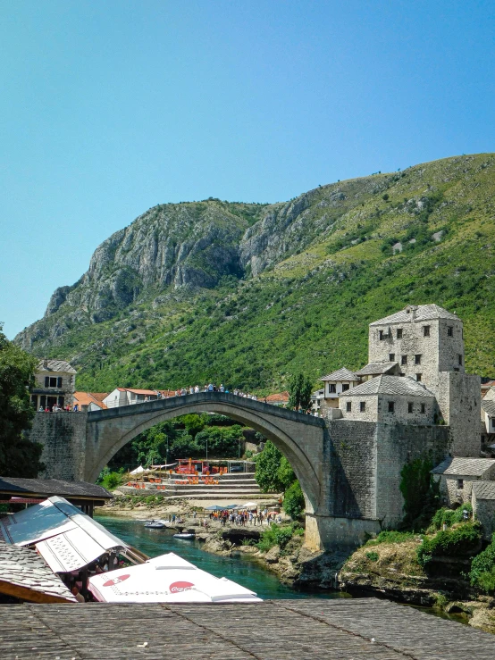 a bridge over water next to a building and mountain