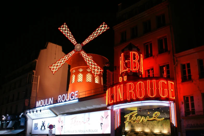 brightly lit shops at night in front of tall buildings