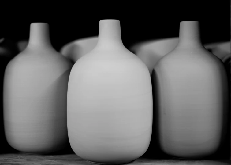 some white vases are standing on a shelf