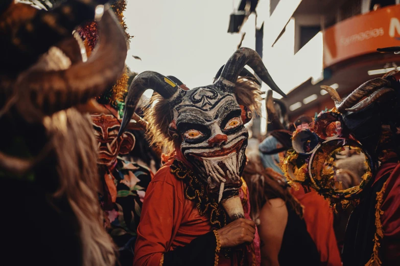 a parade of people wearing masks, including one with a goat's head