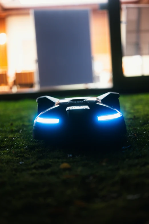 a black remote car on a grassy area with lights on