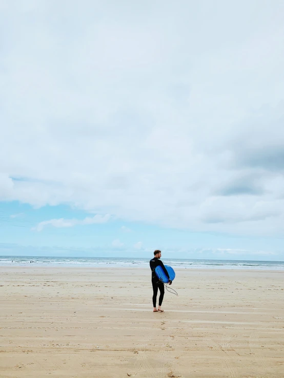 a surfer holding a blue surfboard is walking on the beach