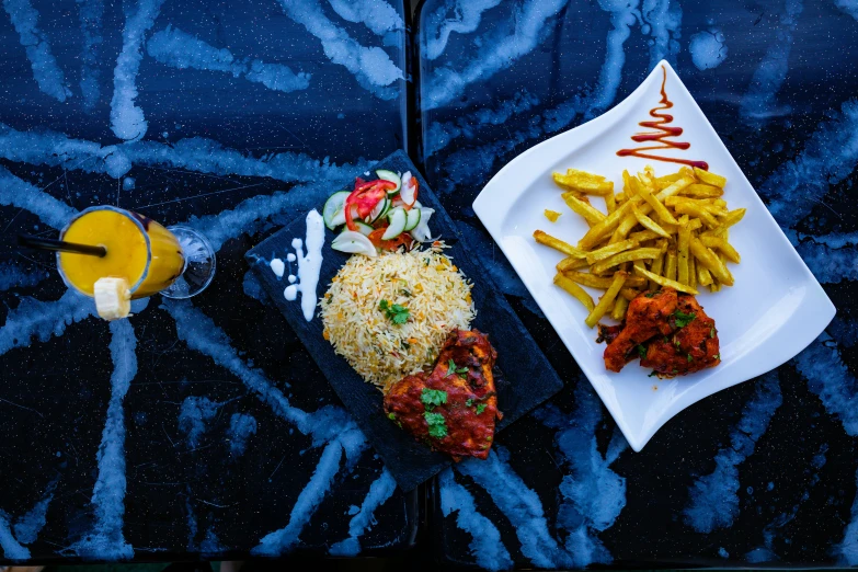 two small plates filled with fries and other foods on a blue tablecloth