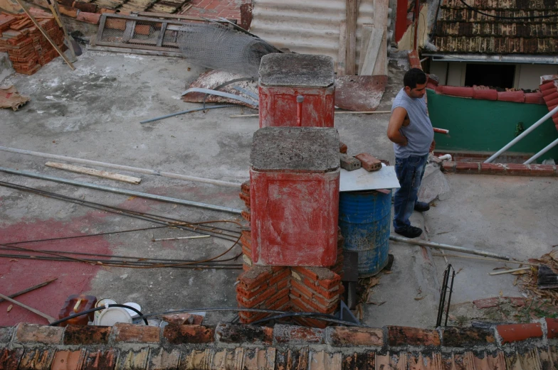 a man standing near some wood and metal pipes