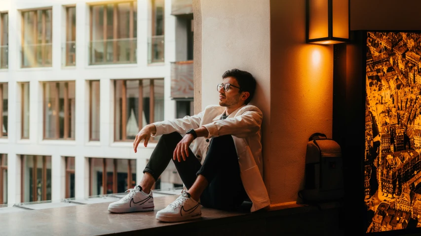 man sitting on the ledge looking out at city