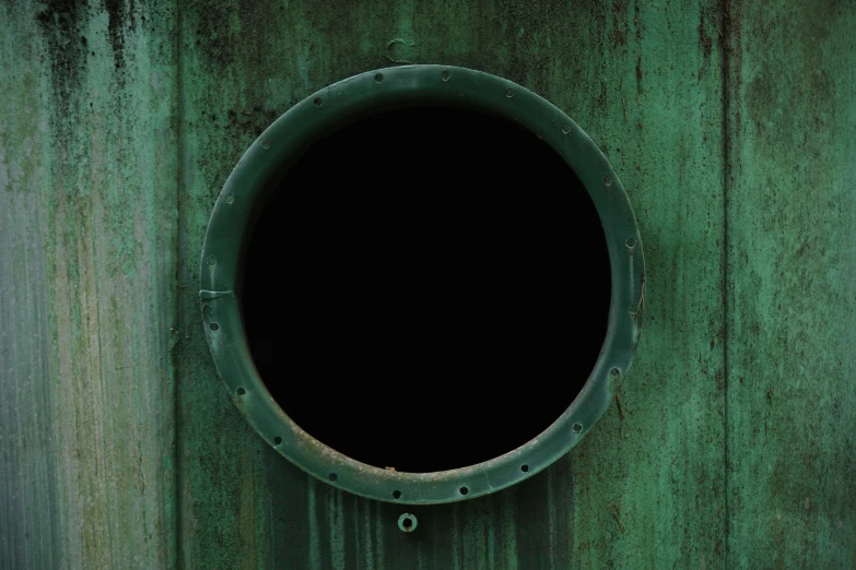 the round opening is in a rusty green steel wall