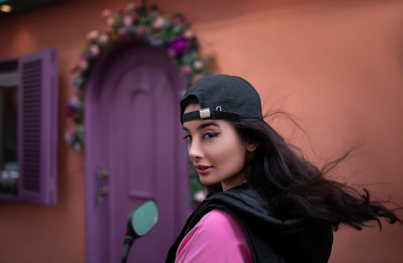 a girl wearing a hat with flowers in the background