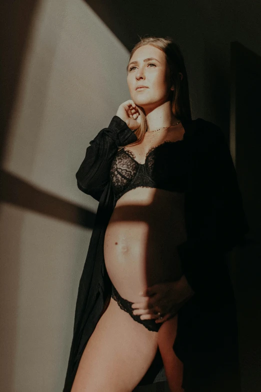 a woman wearing black lingerie poses in front of a dark wall