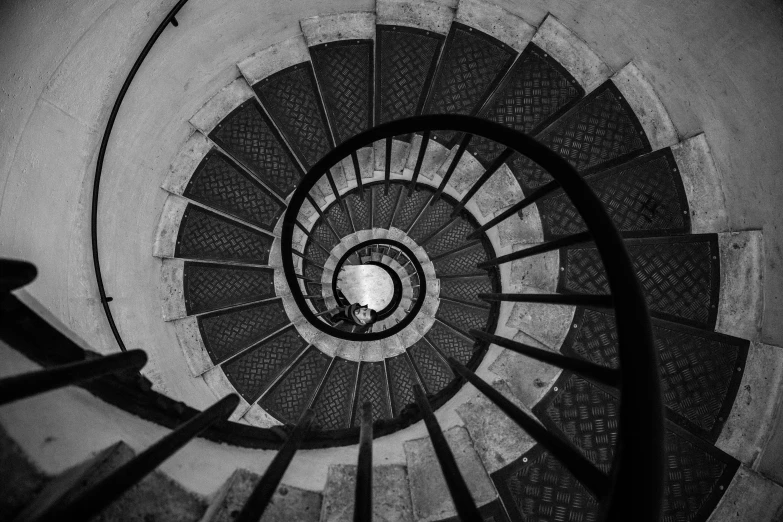 the spiral stairs in a building have a person walking up them