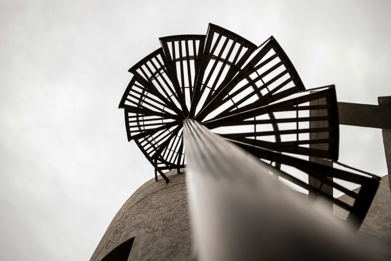 looking up at the top of a water tower with a metal vent that has water coming out