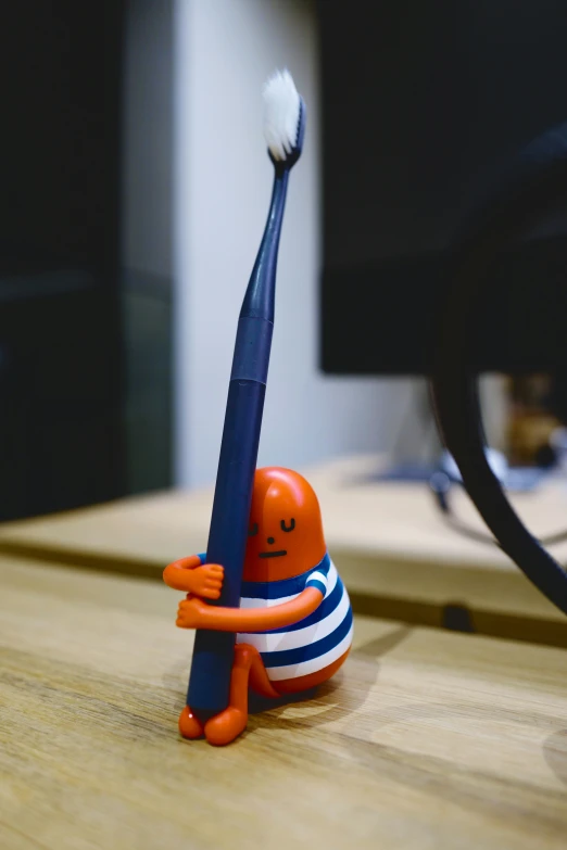 a toothbrush in an orange man's body sitting on a table