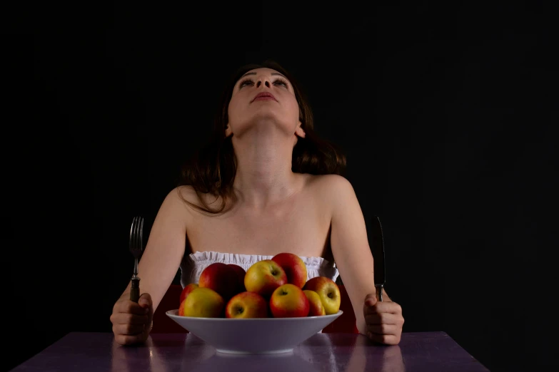 a woman sitting in front of a bowl filled with fruit