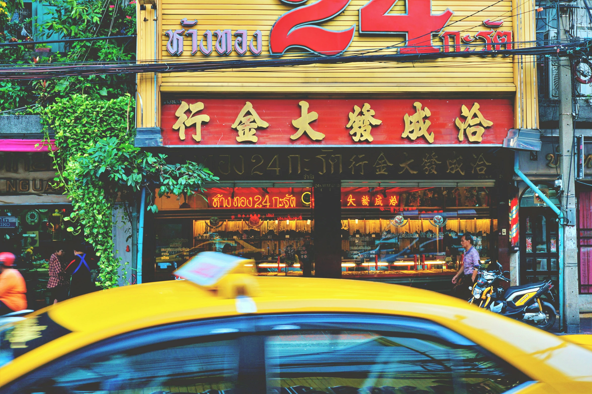 a yellow taxi driving past a shop with a foreign sign