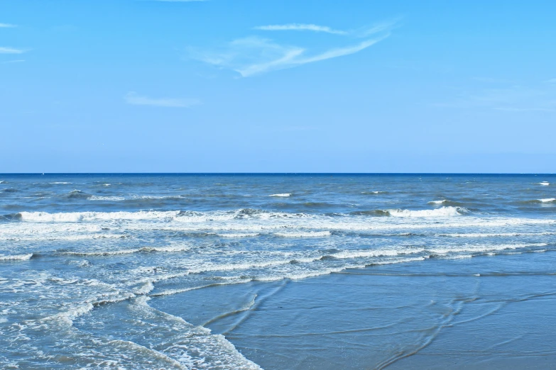 the ocean waves come in toward an empty beach