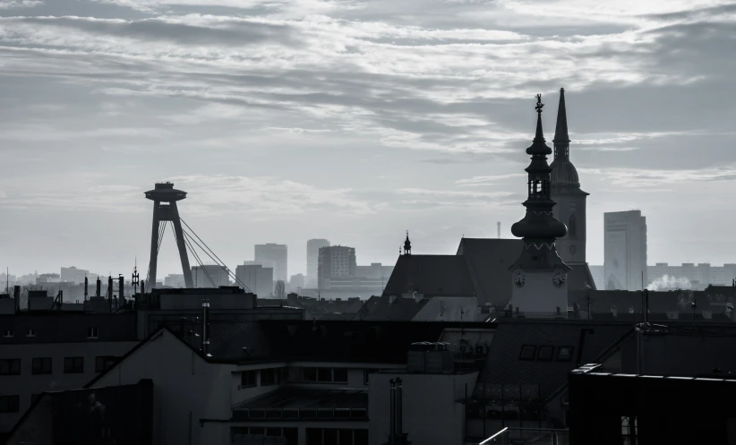 the rooftops and towers of a city against a grey sky