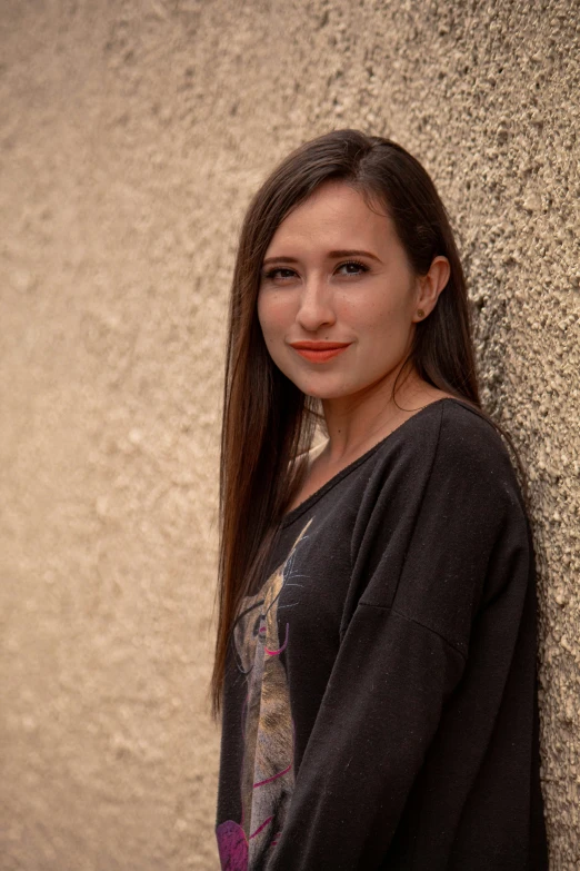 a women with long hair posing by the side of a wall