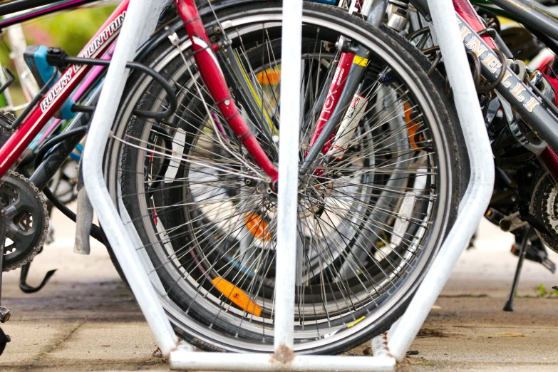 several bicycles stacked up outside with rack in front of them