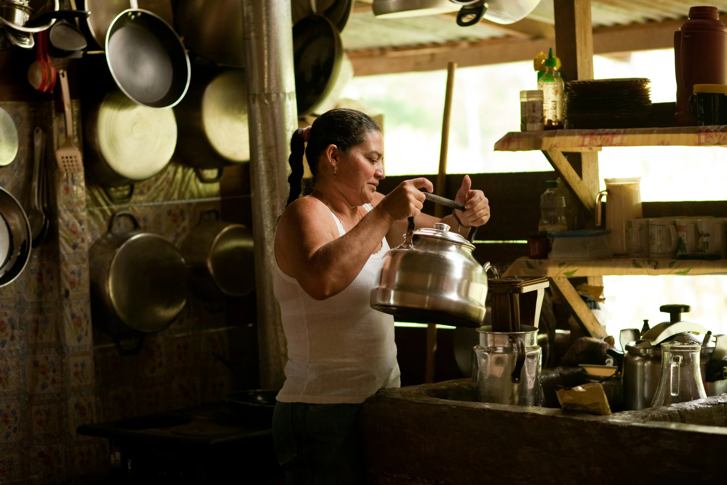 woman drinking milk out of a ladle in a kitchen