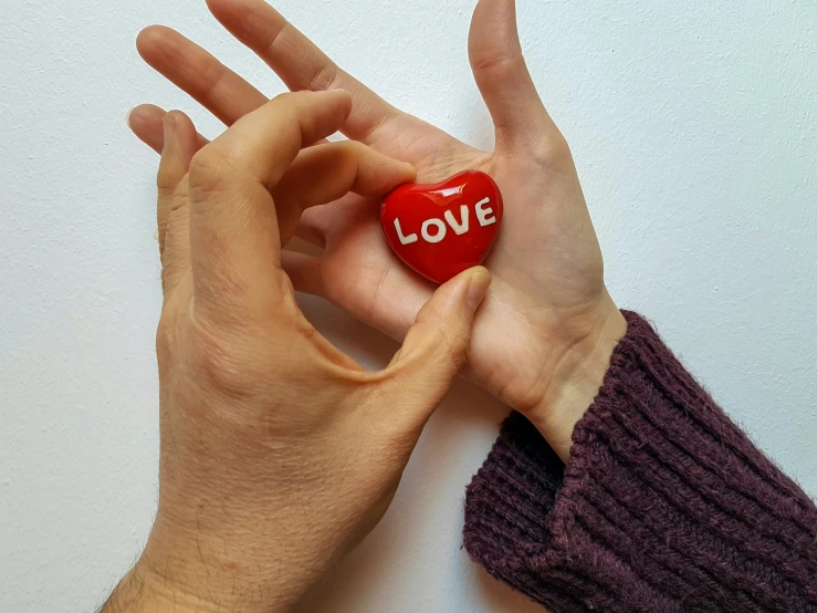 a woman holding up a heart shaped piece to show love